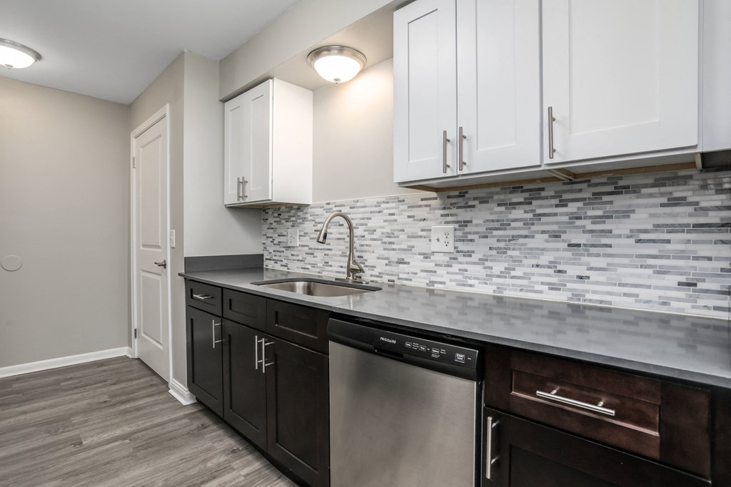 an empty kitchen with white cabinets and a stainless steel dishwasher