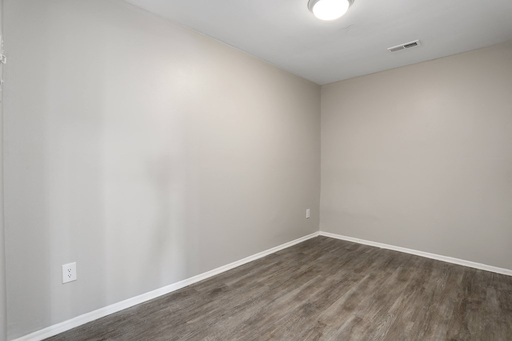 an empty room with wood floors and white walls