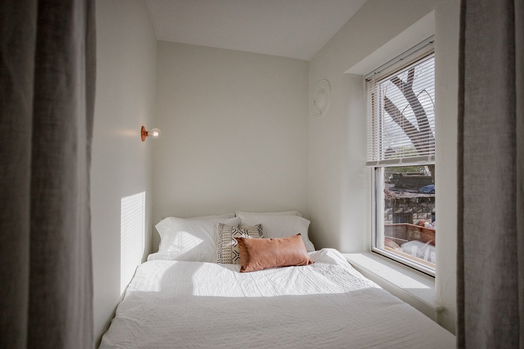 a small bedroom with a bed next to a window