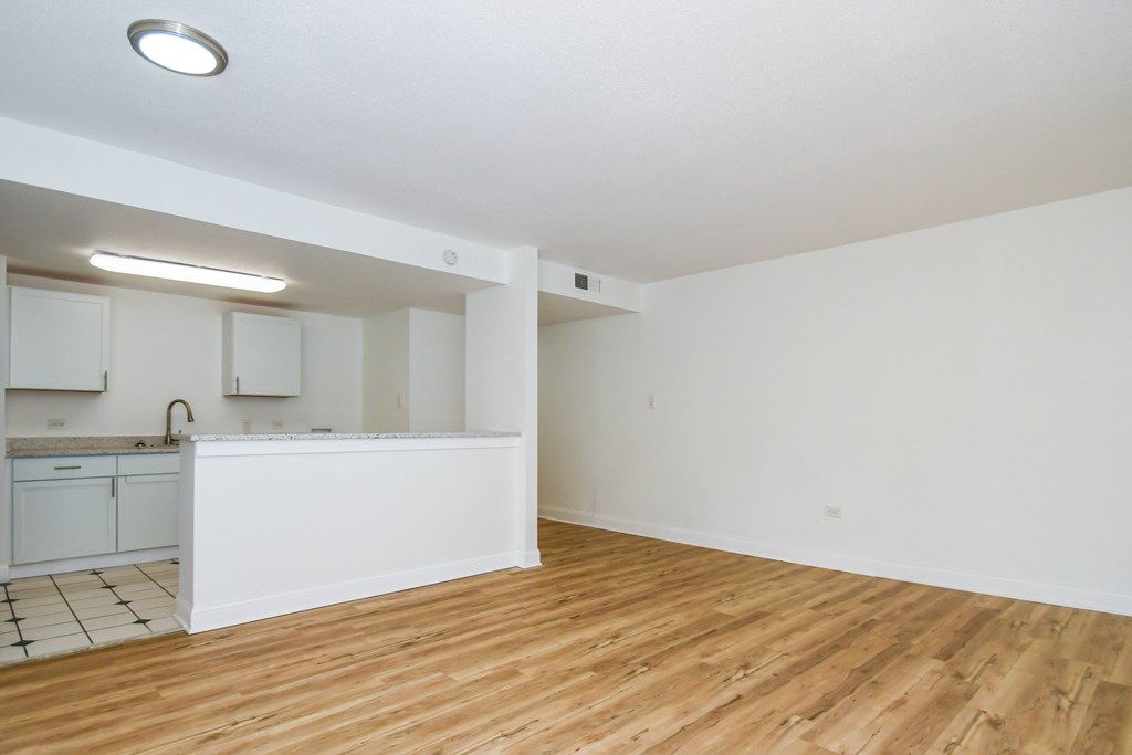 A kitchen with white cabinets and a wooden floor.