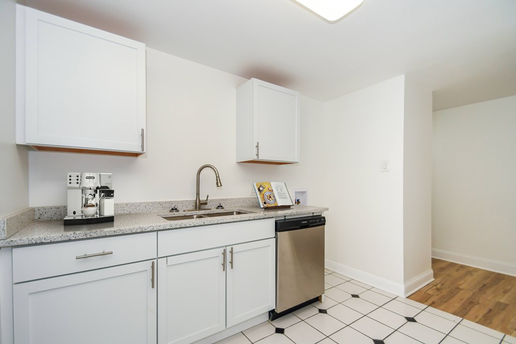 A kitchen with white cabinets and a black and white checkered floor.