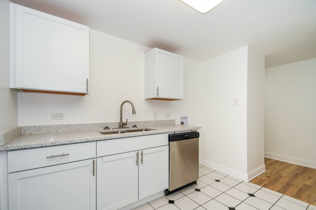 A kitchen with white cabinets and a black and white checkered floor.