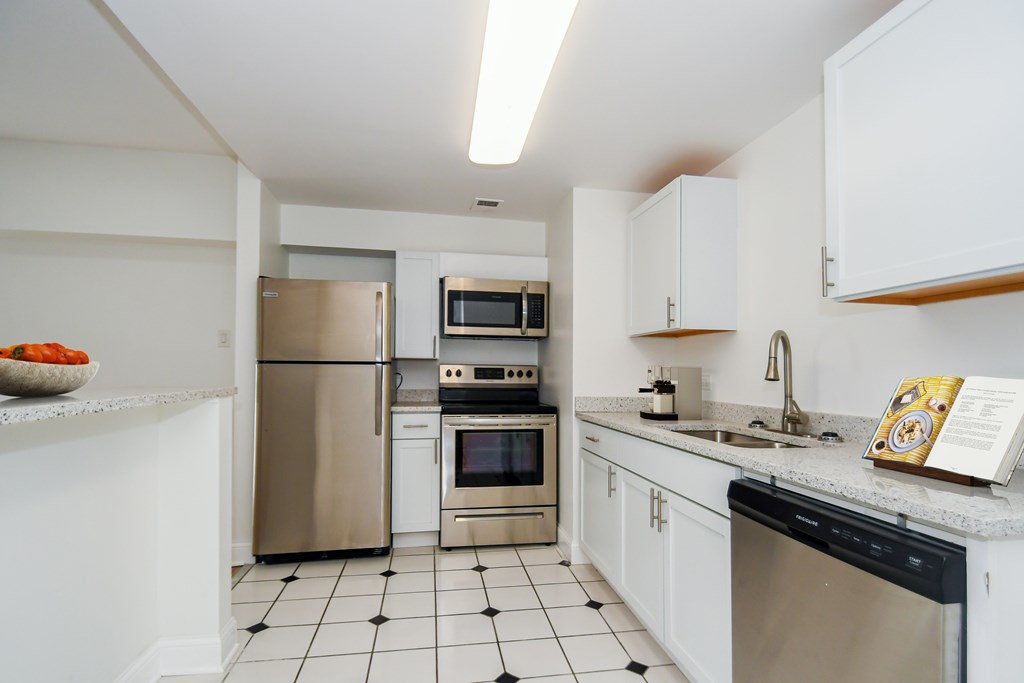 A modern kitchen with white cabinets and stainless steel appliances.