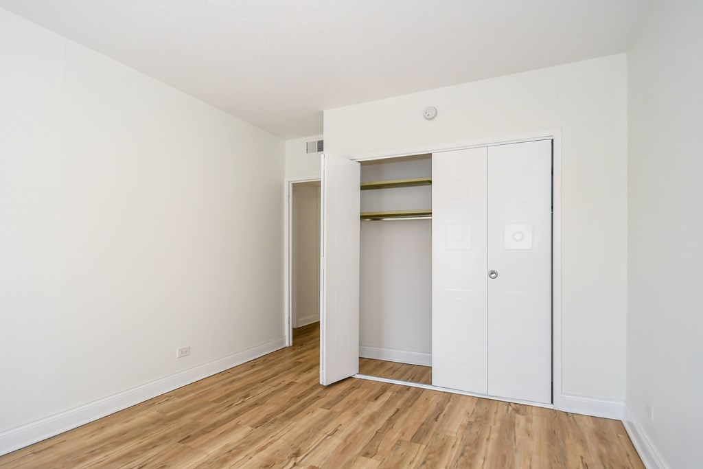 A white door is open to a room with a wooden floor.