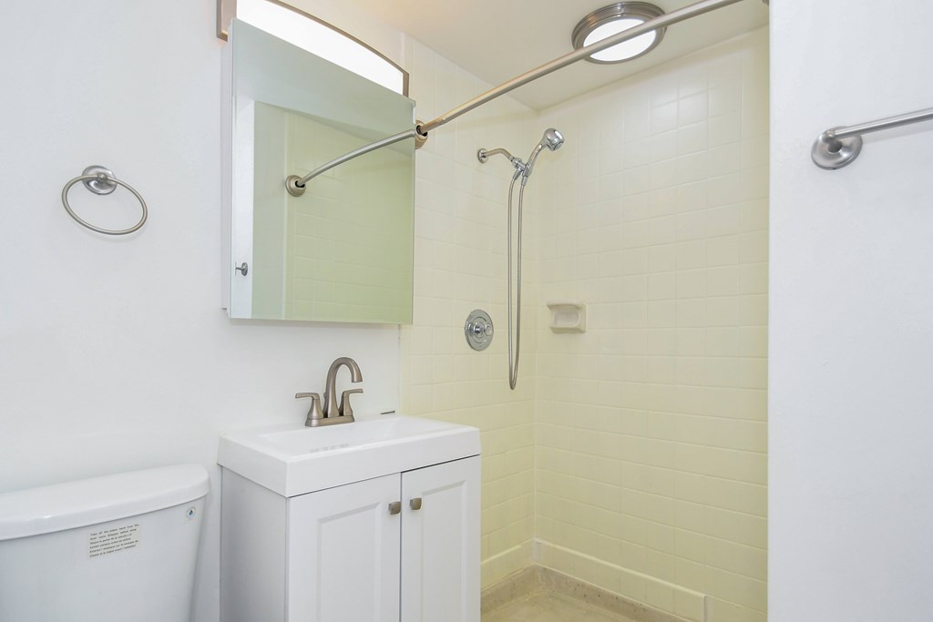 A white bathroom with a sink, mirror, and shower.