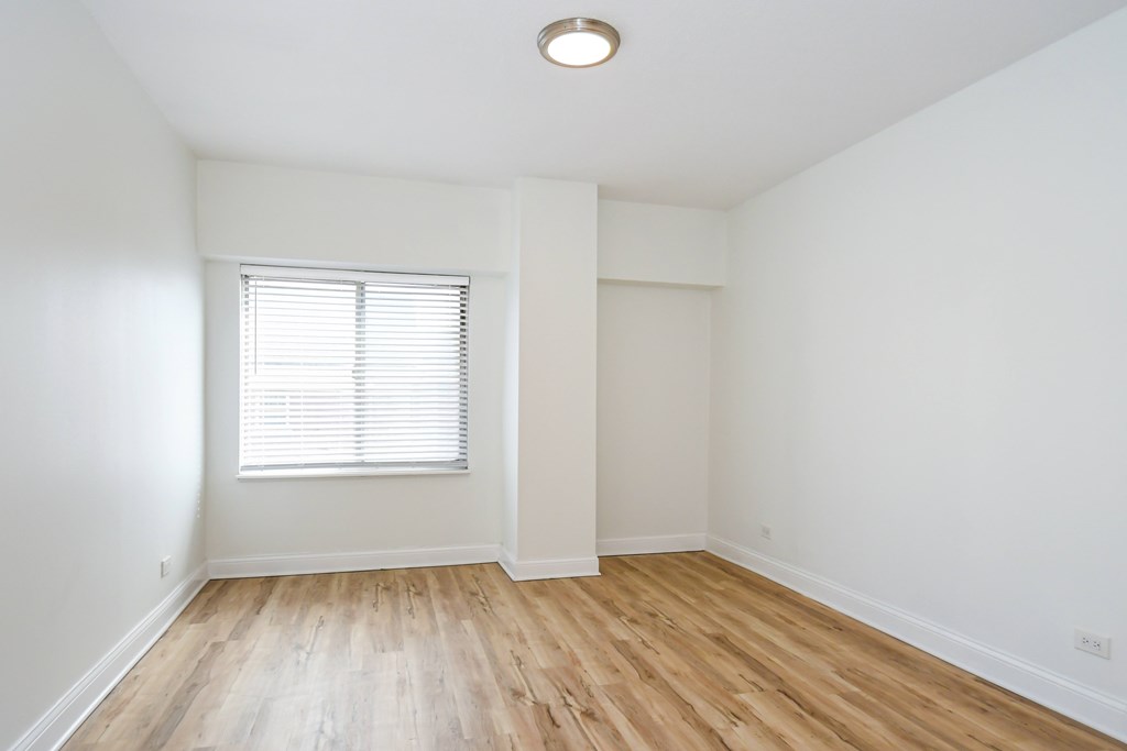 A room with a window and wooden flooring.