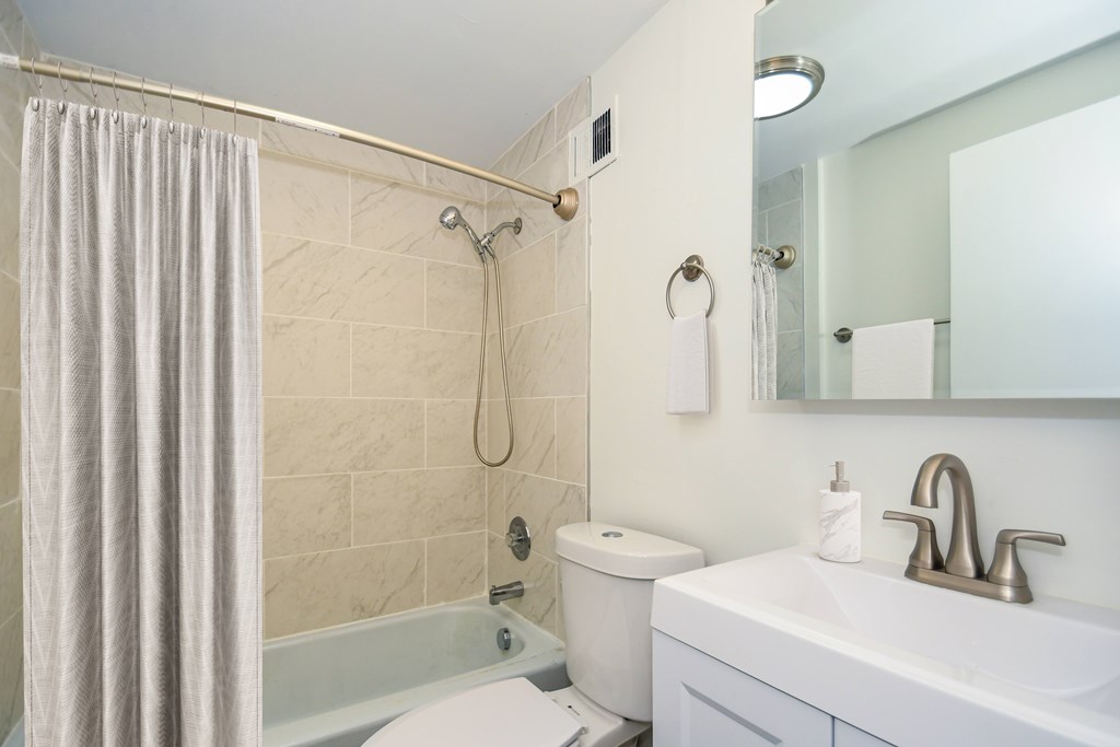 A bathroom with a toilet, sink, and shower.
