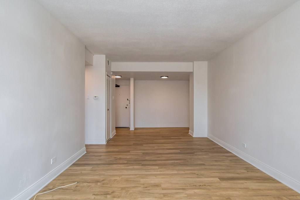 A long, empty hallway with wooden floors and white walls.
