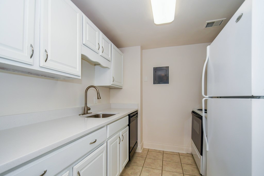 A kitchen with white cabinets and a white fridge.