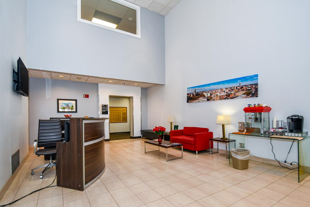 A waiting room with a red couch and a television.