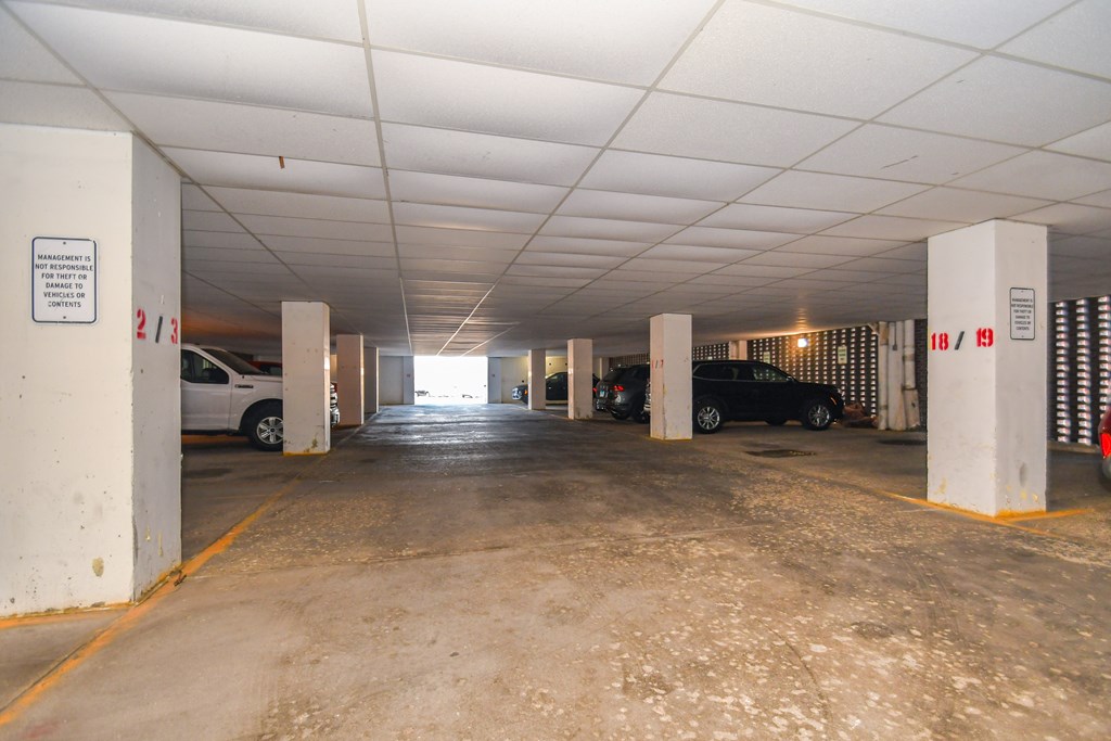 A parking garage with a white car and a black car parked in it.