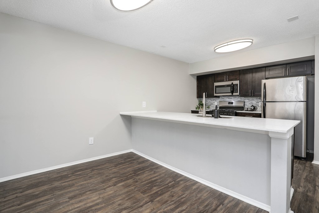 a kitchen with a white counter top and a stainless steel refrigerator
