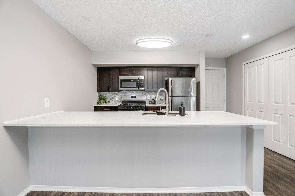 a kitchen with a white counter top and a stainless steel refrigerator