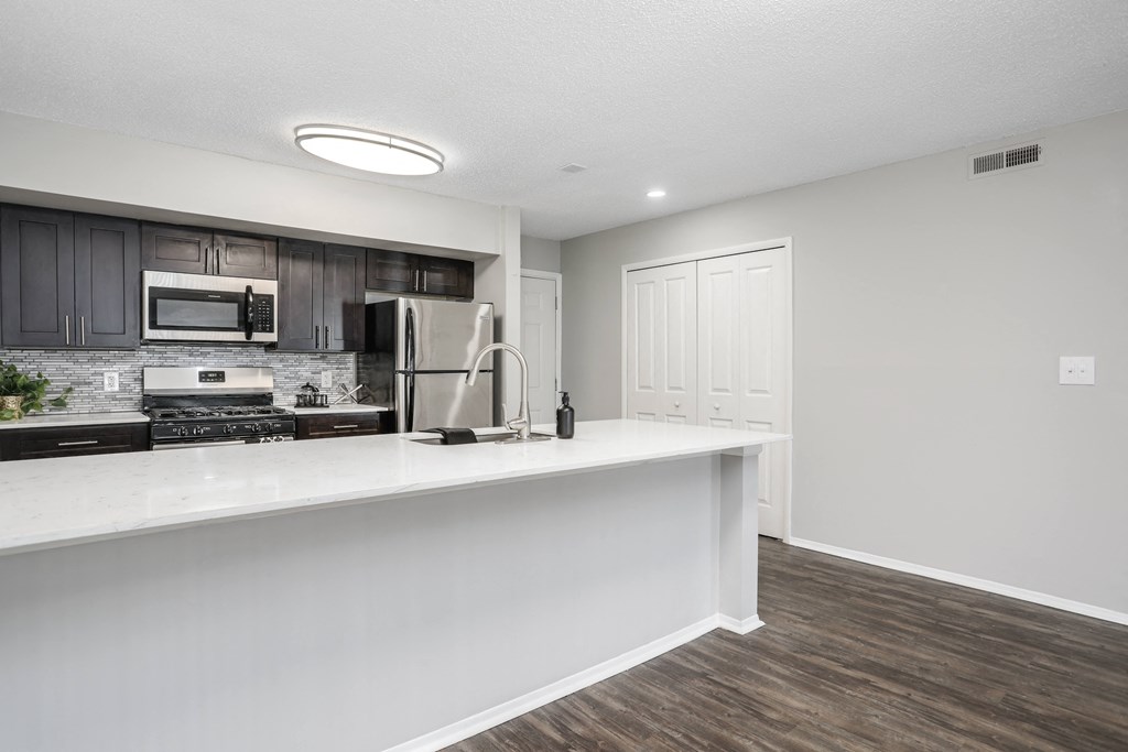 a kitchen with a white counter top and a stainless steel refrigerator