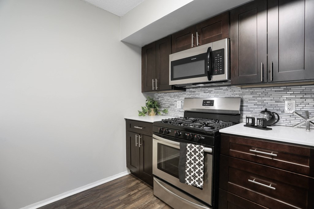 an apartment kitchen with stainless steel appliances and wooden cabinets