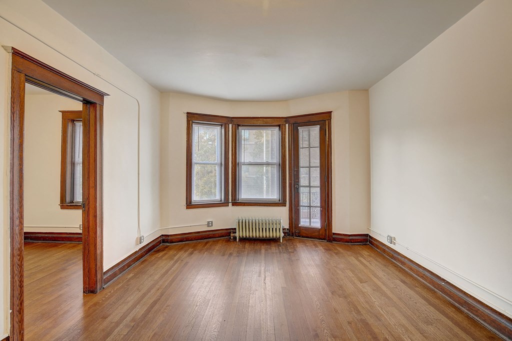 an empty living room with wood floors and a window