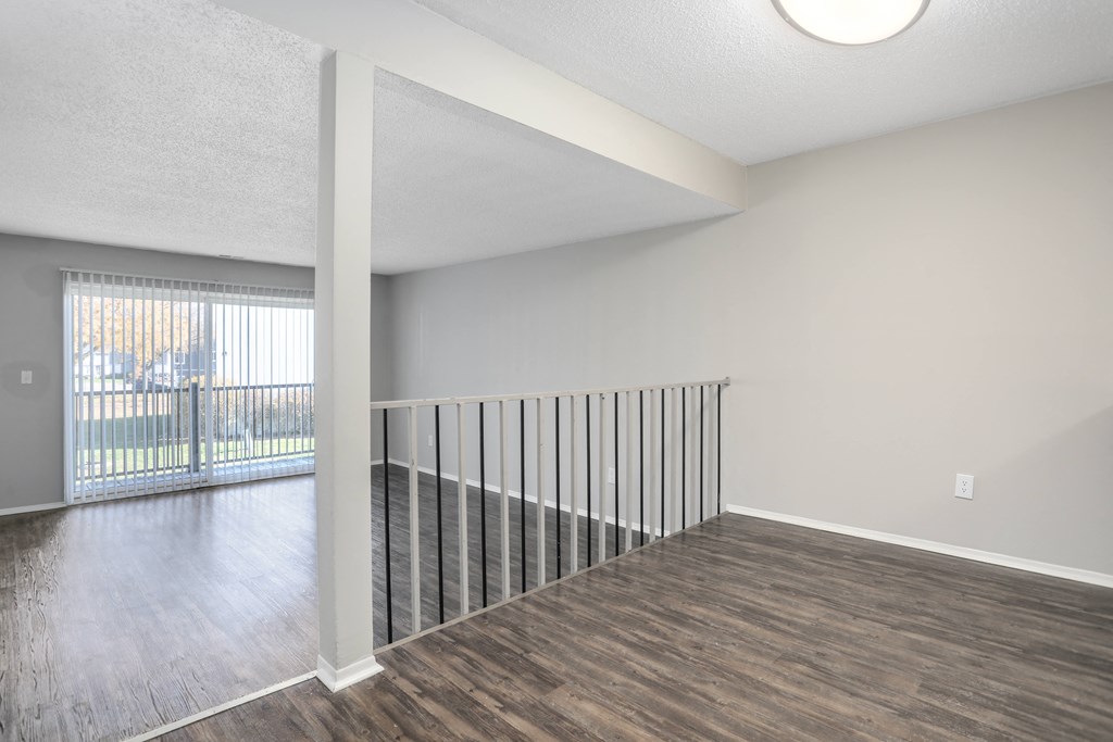 an empty living room with wood flooring and a balcony