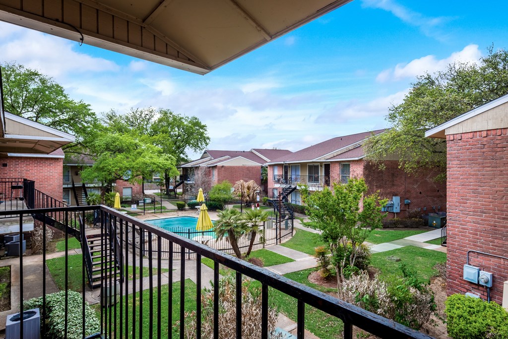 A view from a balcony overlooking a pool and apartment buildings.