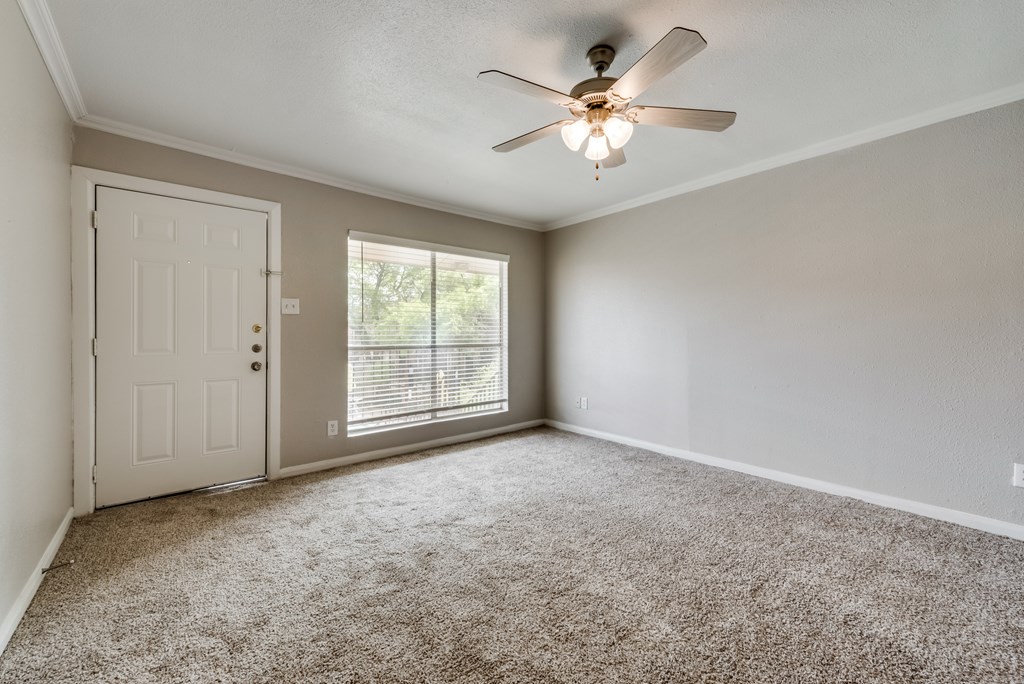 A room with a ceiling fan and carpeted floor.