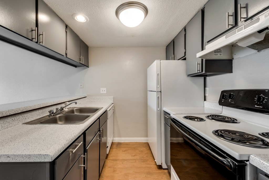 A kitchen with a stove, sink, and refrigerator.