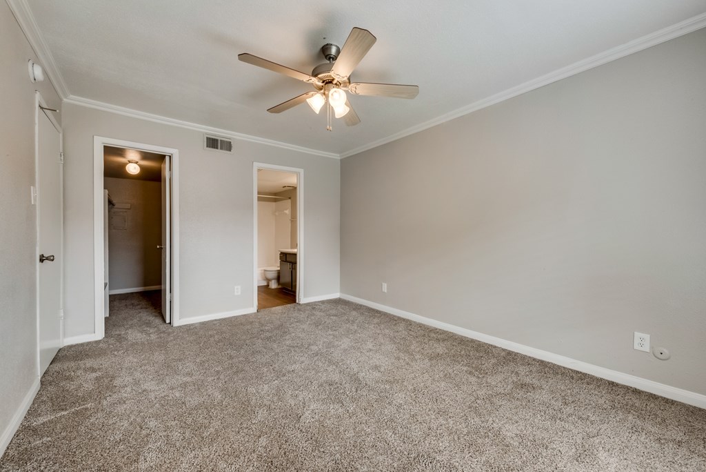A room with a ceiling fan and carpeted floor.