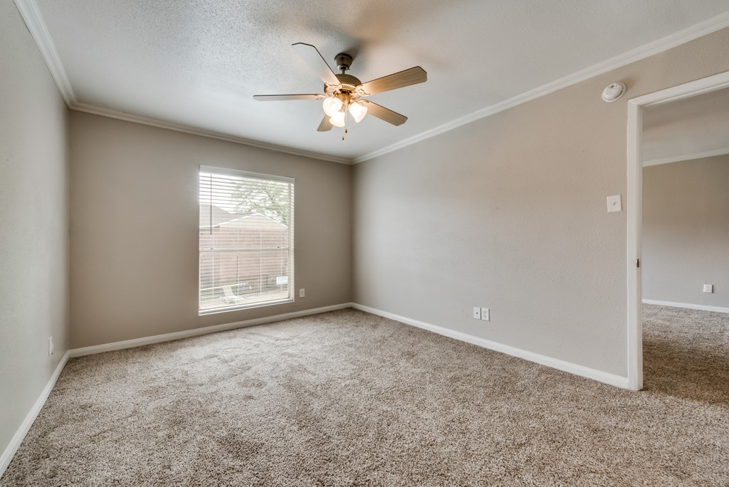 A room with a ceiling fan and carpeted floor.