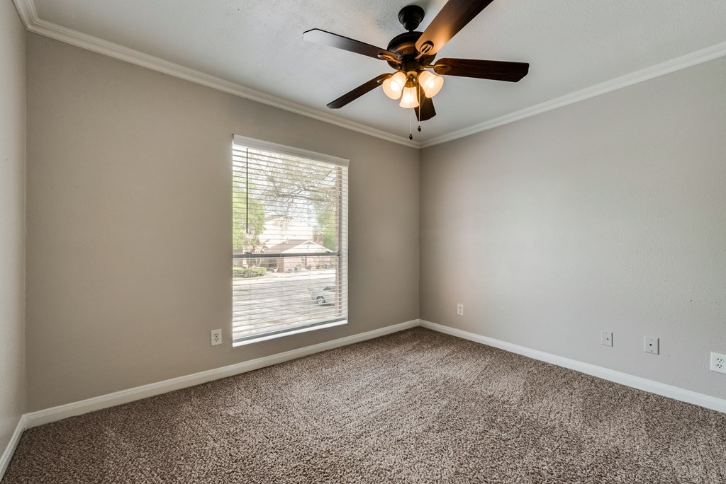 A room with a ceiling fan and a window with blinds.