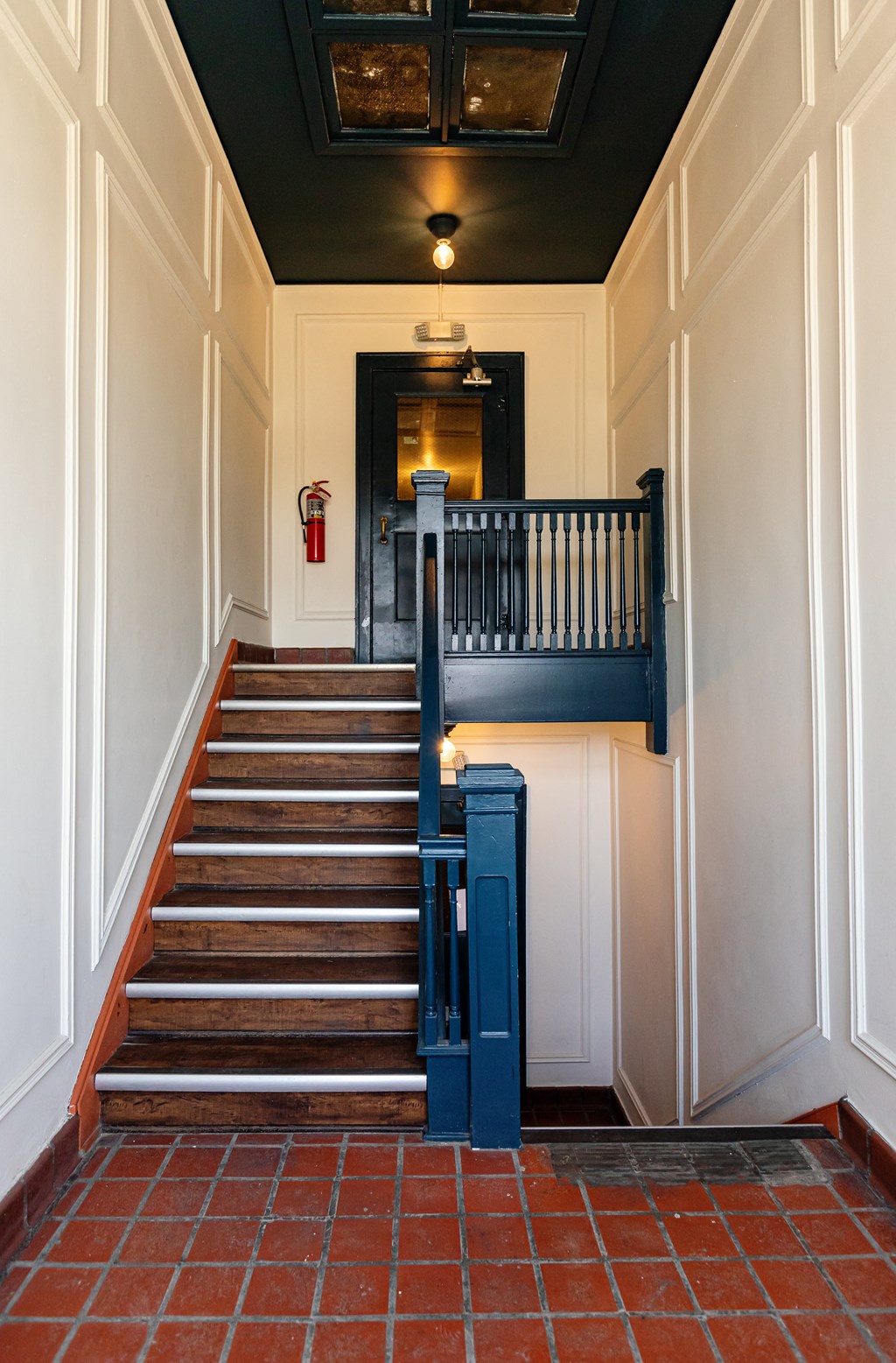 a staircase with a blue railing and a red tile floor