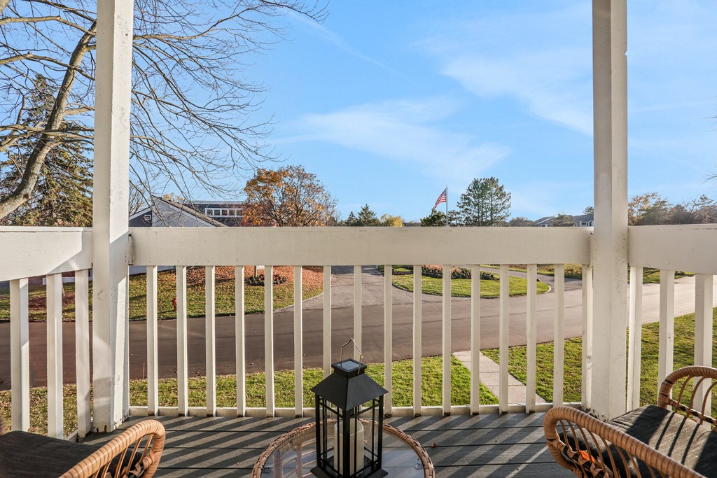 a patio with chairs and a lantern on a porch