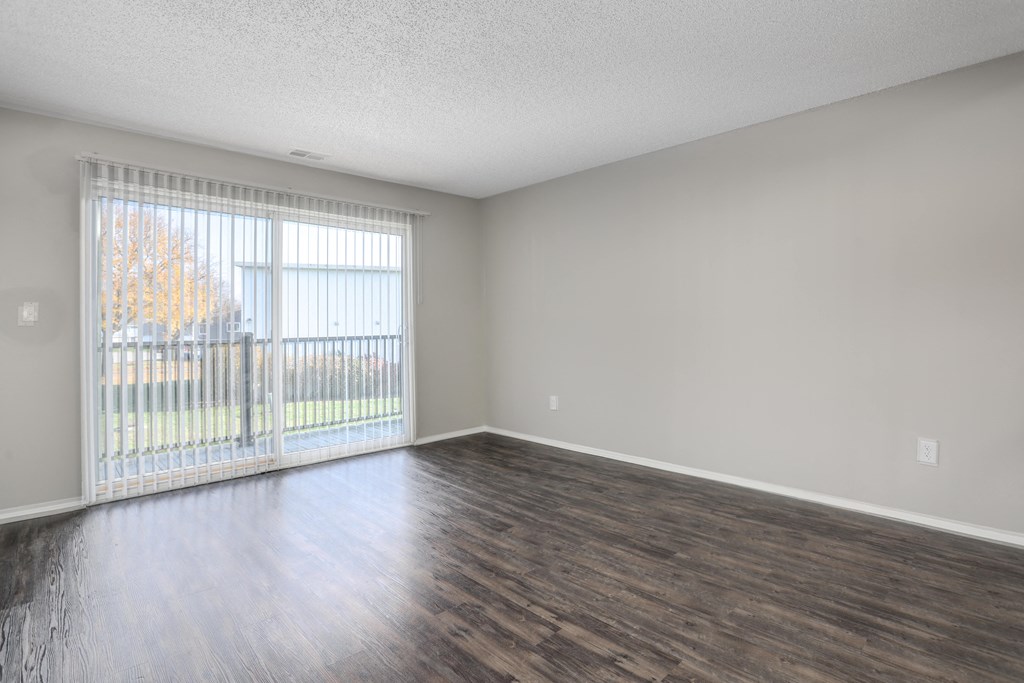 an empty living room with wood flooring and a window