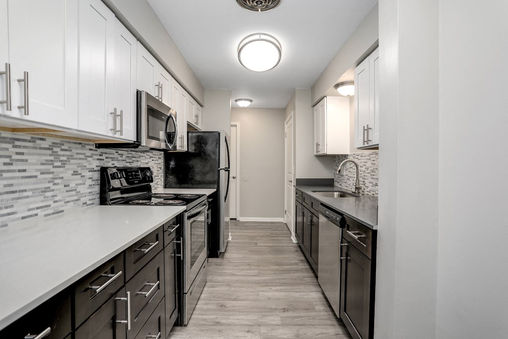 a kitchen with white cabinets and black appliances and a long counter top
