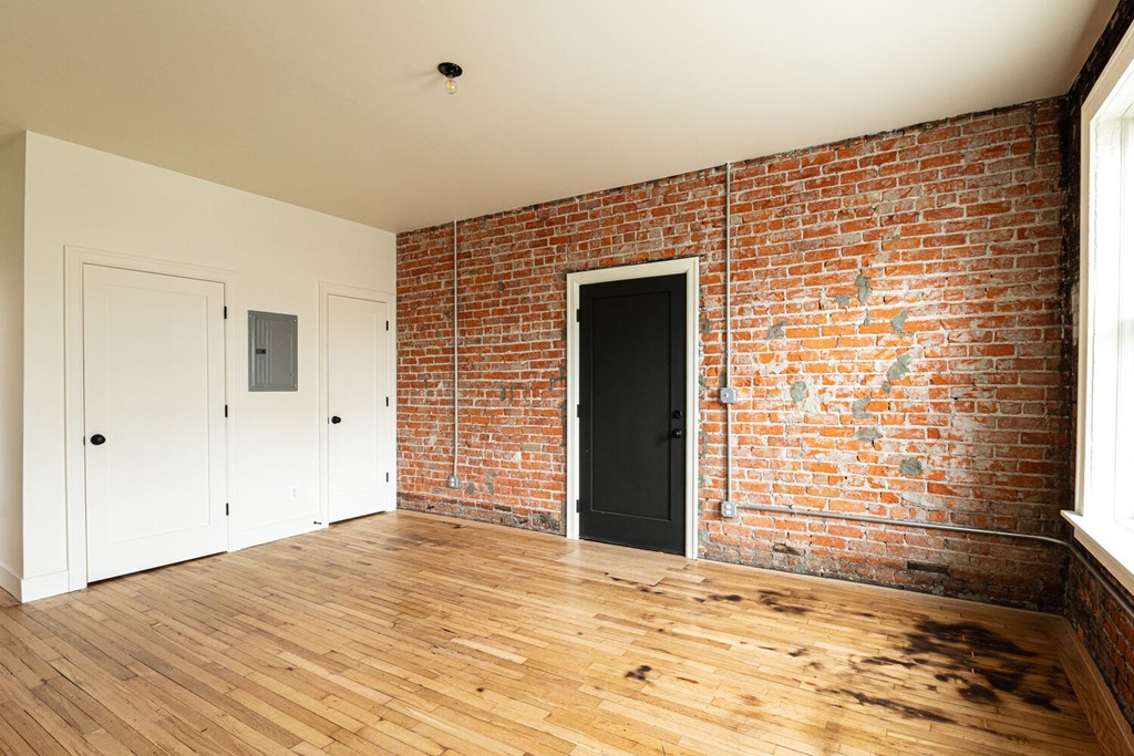 a bedroom with a brick wall and hardwood floors
