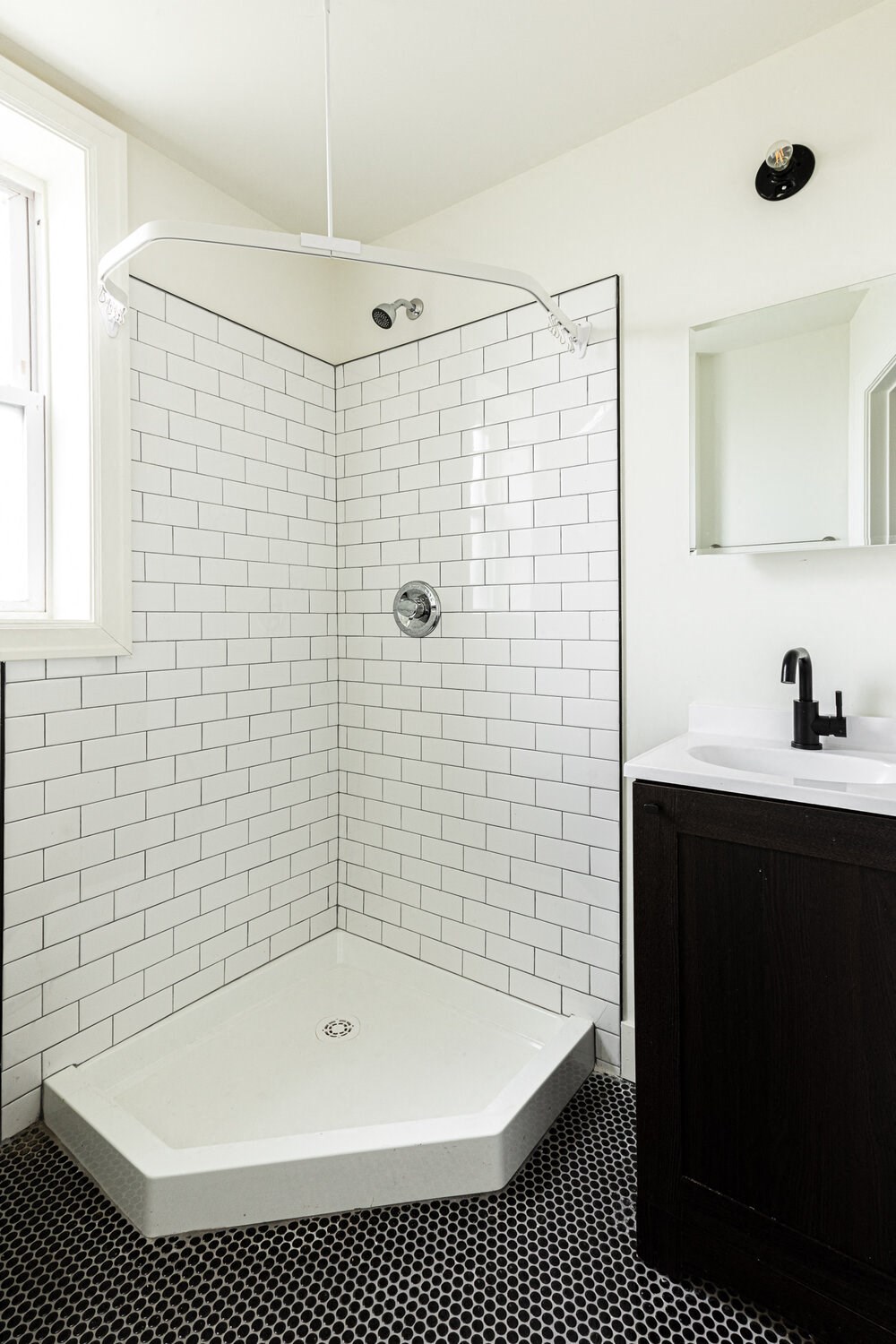 a small bathroom with white subway tile and a black and white tile floor