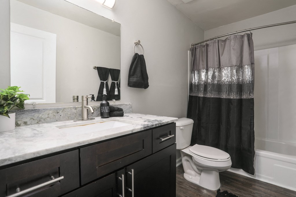 a bathroom with a black shower curtain and a sink and a toilet