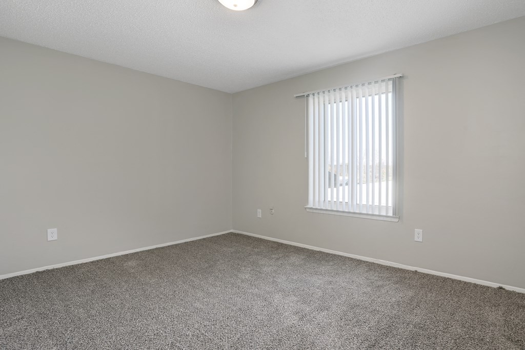 an empty living room with a window and carpet