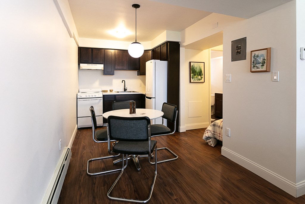 a room with a small table and chairs and a kitchen in the background