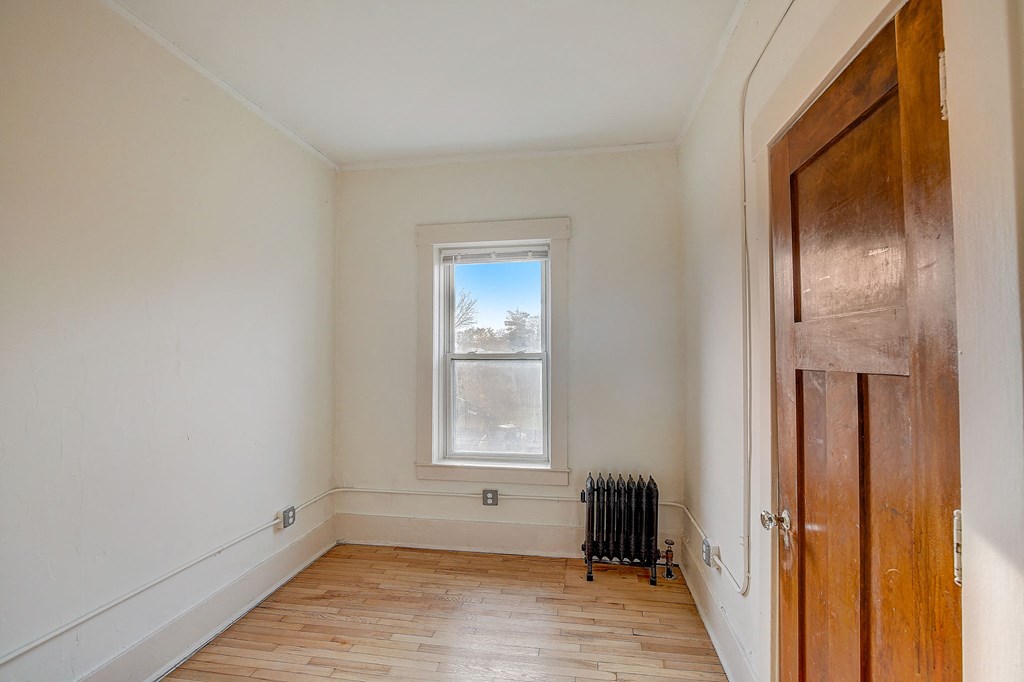 a room with a wood floor and a window and a wooden door