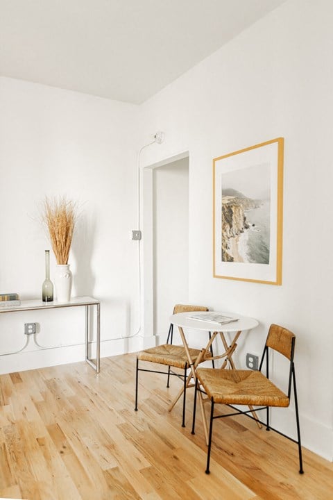 a dining area with a small table and two chairs and a large painting on the wall