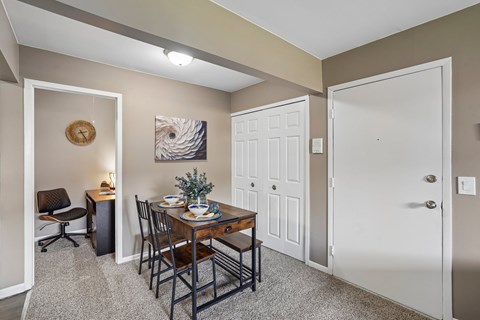 A dining area with a table set for two and a painting on the wall.