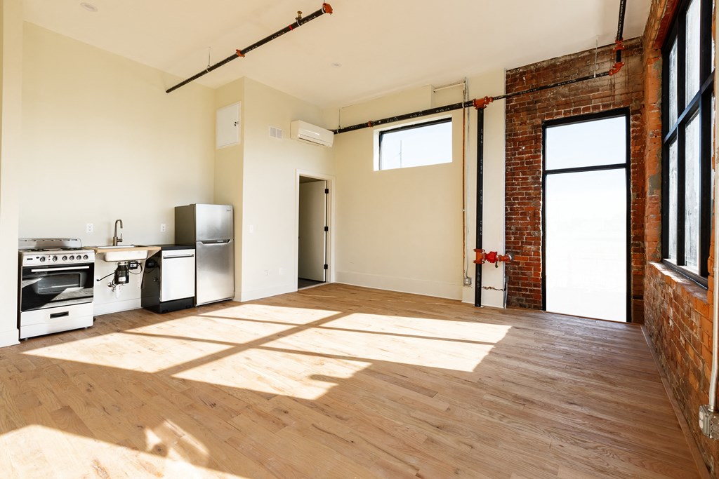an open living room with a kitchen and exposed brick wall