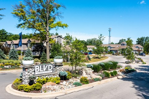 a garden area with a sign and a house in the background