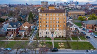 an aerial view of a large brick building in a residential area with a cityscape in the