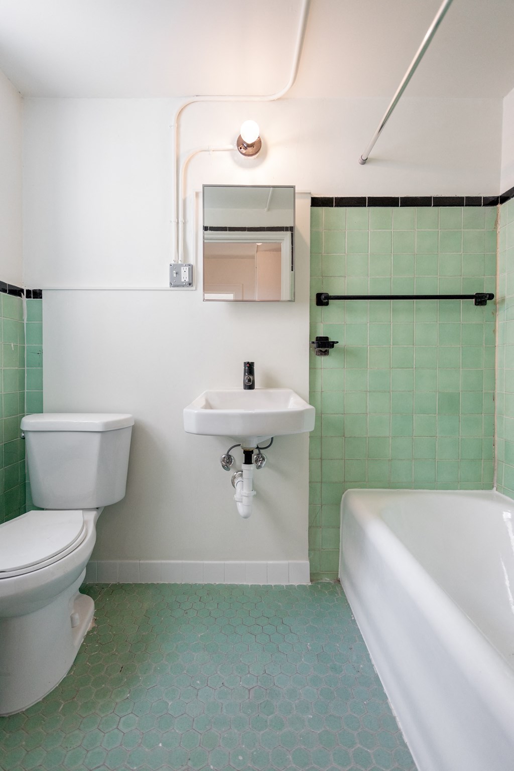 a bathroom with green tiles and a white toilet