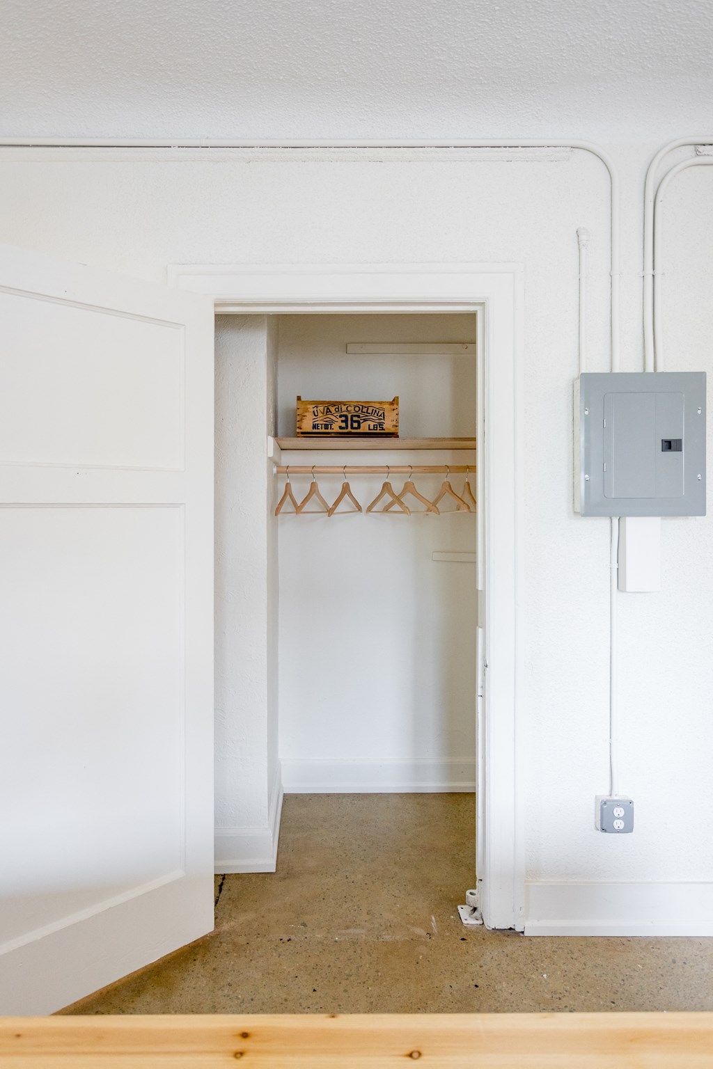 a room with a white wall and a white door with a bookshelf in it