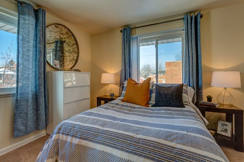 A bedroom with a large bed and a round mirror on the wall.