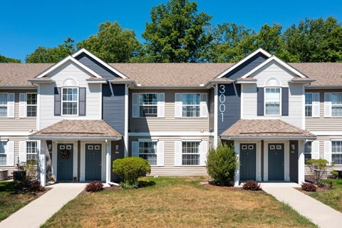 a large white house with blue doors and a lawn