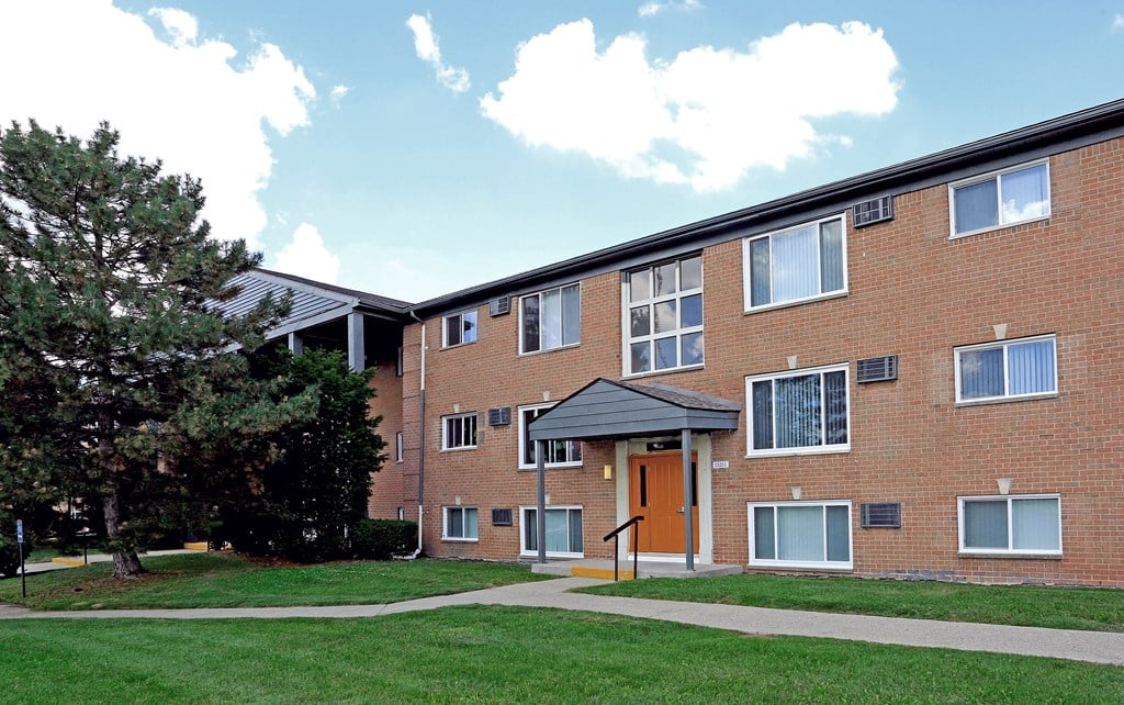 a brick apartment building with a sidewalk and grass