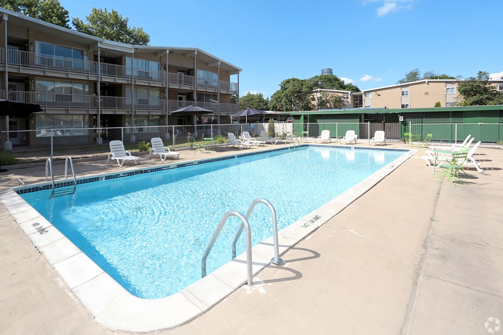 blue pool with ladder surrounded by white lounge chairs