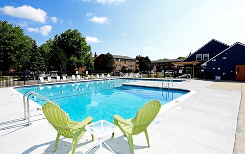 Two green chairs are placed on the edge of a blue swimming pool.