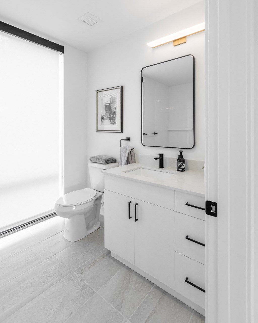 a white bathroom with a toilet and a sink and a mirror